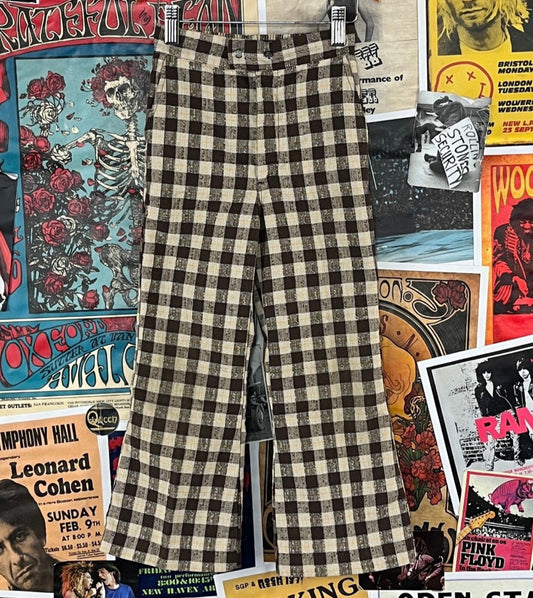 Vintage unisex kids retro 60s-70s khaki beige, brown, and yellow plaid print flared trouser pants by Buster Brown. Made in the USA of 67% polyester and 33% cotton. Features an elastic back waist, zip fly, and snap buttons. Tagged size 6X-7, we estimate it to fit size 6X-7 slim. Please check measurements for accurate sizing. Has some light dirt wear on the knees, but is in otherwise good, pre-owned condition.