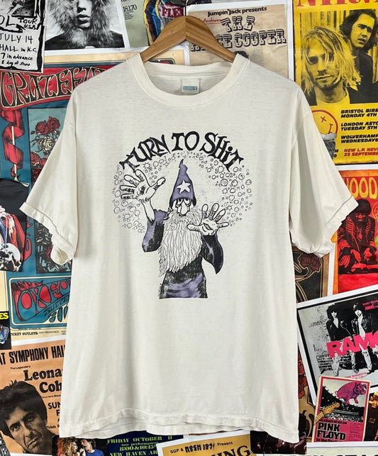 Funny vintage 90s white short sleeve Turn to Shit wizard graphic crewneck t-shirt. Made of 100% cotton. Tagged adult size large. Selling in as is condition. Has faint underarm discoloration, several light stains through out, few small holes including an underarm hole, and light discoloration through out. See images and video for all flaws.