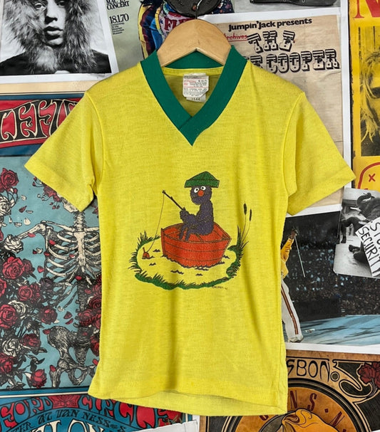 Vintage kids unisex 1970s-80s yellow and green short sleeve Sesame Street the Muppets Jim Hansen Grover fishing graphic pullover v-neck pajama t-shirt top. Made of 100% polyester by JCPenney. Tagged kids size 6-7, which we estimate ti fit ages 5-7. See measurements for sizing. Has piling through out, but is in otherwise good, pre-owned condition.