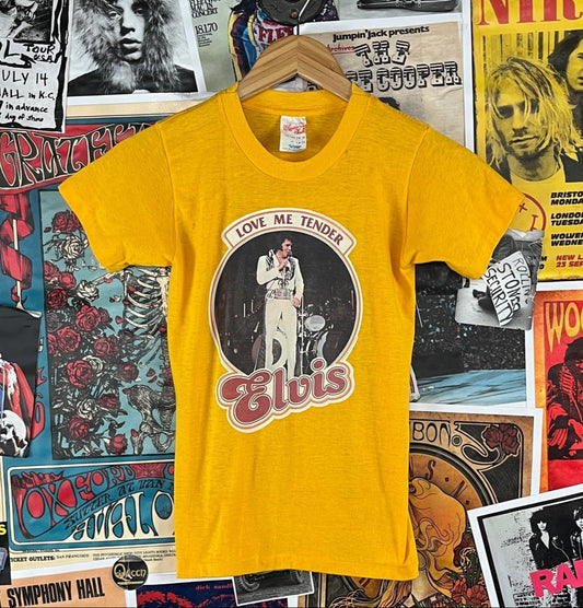 Vintage kids unisex retro 1970s yellow short sleeve single stitch Love Me Tender Elvis iron-on graphic crewneck t-shirt by Harbor Town. Made of 50% polyester and 50% cotton in the USA. Tagged kids size large ages 14-16. We estimate it to best fit kids size 12, ages 9-10. Has a couple spots and is near threadbare.