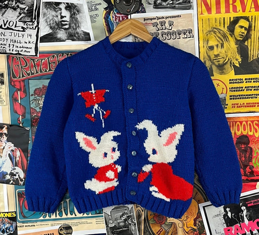 Sweet girls kids vintage retro 1960s blue, red, and white hand knit cardigan sweater top with sweet double sided bunny rabbits. Buttons up the front and is in great, pre-owned condition. There is no tag size as it's likely handmade. We estimate it to fit girls size 8, ages 7-8. Feels like an acrylic.